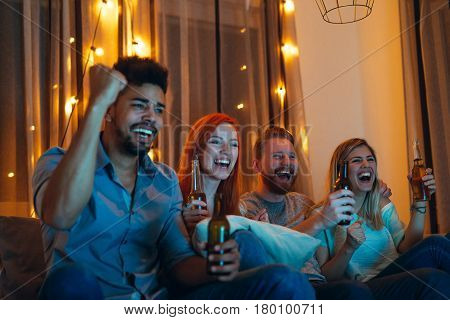 Photo of friends enjoying watching a game at home.