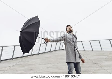 Handsome Guy holding umbrella on windy day
