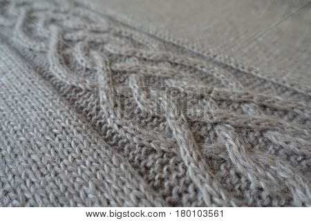 Close-up of grey handmade knit fabric with plait pattern