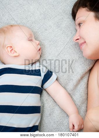 Happy mother with sleeping baby at home