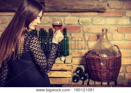 Elegant beauty lady long hair full make up wearing black dress tasting wine in rural cottage interior celler