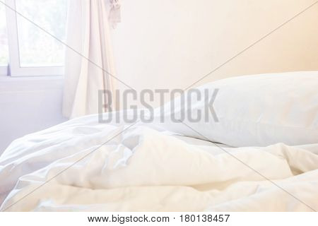white pillow and blanket with wrinkle messy on bed in bedroom with lighting upper left side from sleeping in a long night winter.