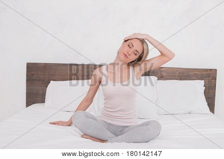 Young woman sitting on bed practice yoga pose
