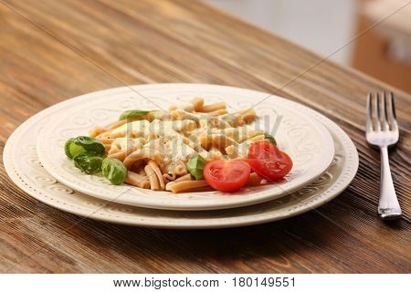Plate with delicious pasta and cheese sauce on wooden table