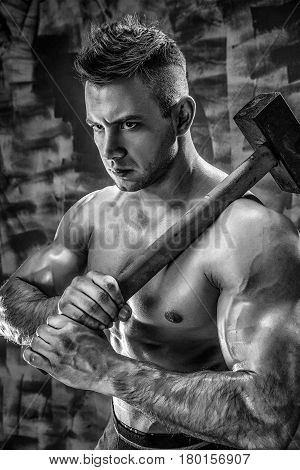 athlete and hammer. guy with a nice toppless muscle fitness body, bodybuilder coach hold big metal hammer