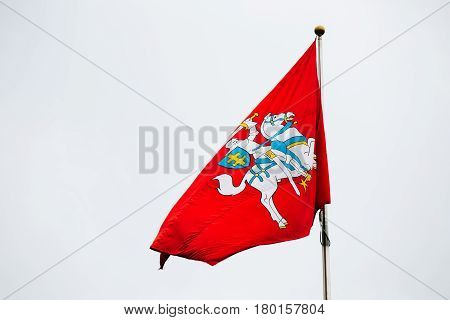 Coat Of Arms Of Lithuania On The State, Historical, Flag Of Lithuania, Waving On Flagpole At White Sky Background.