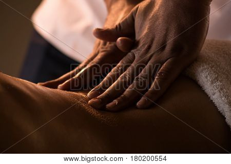 Massage closeup view with hands of professional masseur. Charming lighting