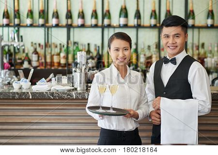 Smiling waiter and waitress with drinks and towel