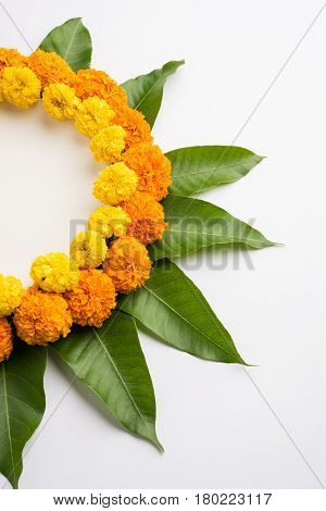 flower rangoli made using marigold or zendu flowers and mango leaves over black background with copy space in the middle, selective focus
