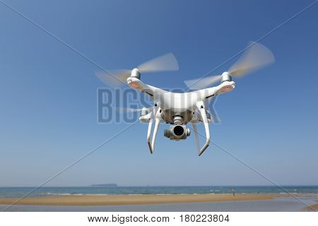 KAGAWA, JAPAN - APRIL 03, 2017: White remote controlled Drone Dji Phantom4 Pro equipped with high resolution video camera hovering in air with shore and blue sky in the background