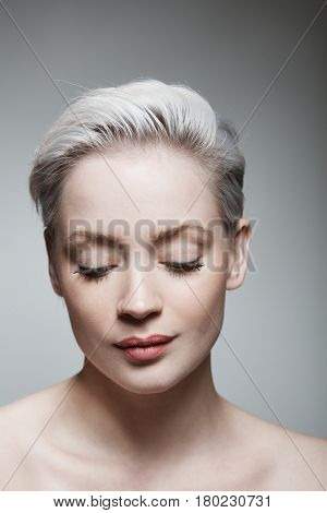 Young woman with short hair looking down.