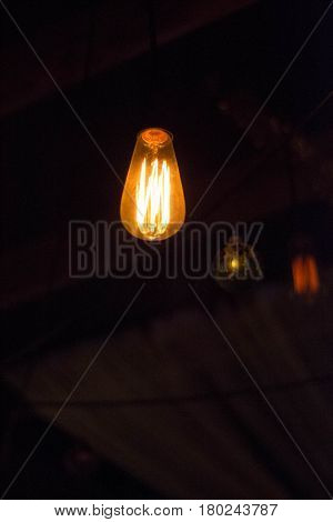 Minimalis. Stylish chandelier in the form of a conventional bulb. Light in the dark. Lighting of the room.
