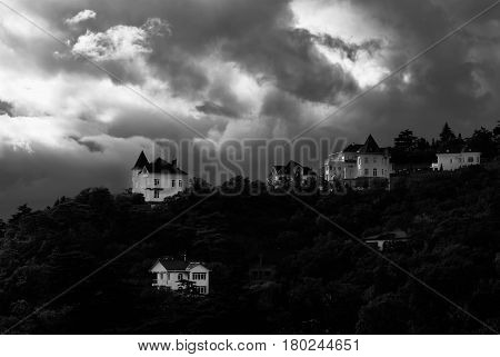 Early fall landscape with pre-stormy sky and new houses in Crimean Mountains Ukraine - black and white obscure version.
