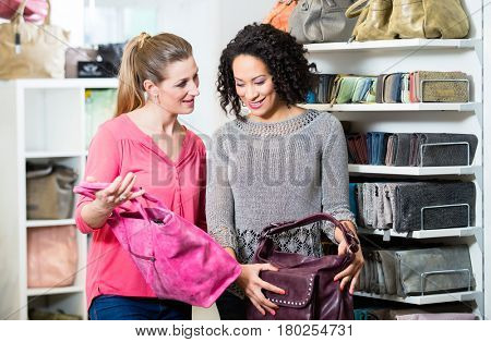 Girlfriends in fashion store buying handbag 