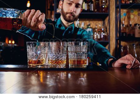 The barman pours alcohol into a glass. Close-up.