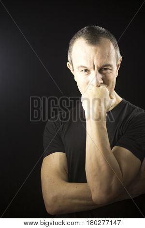 Attractive handsome slim healthy man aged in 40's in black t-shirt against plain black studio portrait background.