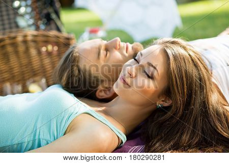 Couple in park on picnic. top view of a couple in love lying on a picnic plaid. Young loving couple think about their dreams at picnic outdoors.