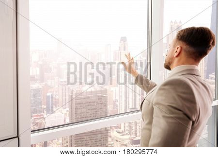 One more touch. Serious professional businessman using transperant screen and standing in the office while being involved in work