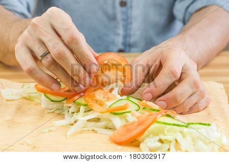 Making vegetarian flat bread sandwich. Male hands laying fresh vegetables on lavash flat bread for making vegan kebab sandwich