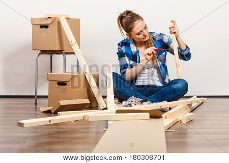 Woman Moving Into Apartment Assembly Furniture.