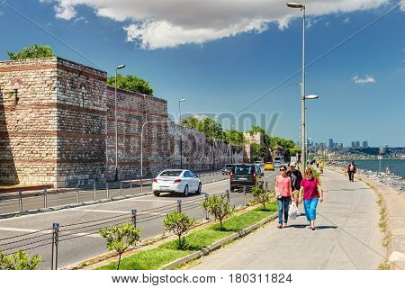 ISTANBUL - MAY 27: People walk along the promenade past the ancient sea walls of Constantinople on May 27, 2013 in Istanbul, Turkey. In ancient Constantinople had the most powerful fortifications in the world.