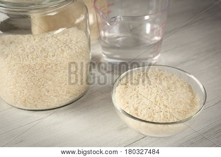 Kitchen ware with rice and water on wooden table