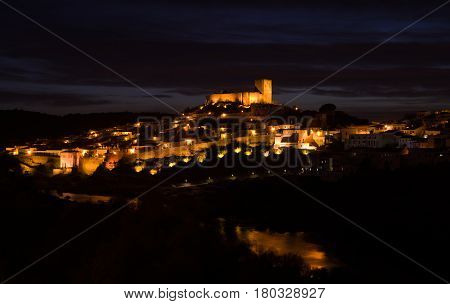 Mertola castle and the oldest part of town lighted at night over the River Guadiana down the slope. Alentejo Portugal.