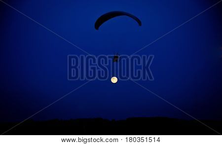 Skydiver flying against the sky with the moon
