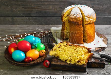 Easter sweet bread Orthodox kulich paska willow twigs. Easter Colorful eggs on gray wooden background. Holidays breakfast. Palm Sunday. Space for text.