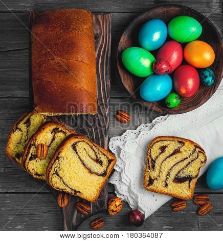 Easter card. Easter treat cozonac painted chicken and quail eggs. Easter willow pecans nuts. Rustic style gray wood background. Top view.