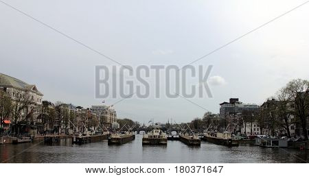 Amsterdam in April 2016. Netherlands. Big canal with houseboats and sluices.