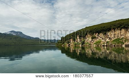 Beautiful coast of the Kurile Lake is reflected in the water.