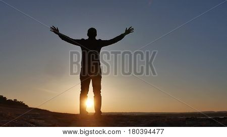 freedom. Man stands on cliff sunset silhouette hand lifestyle in the sides