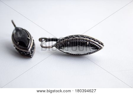 Silver earrings with a black gem on a white background