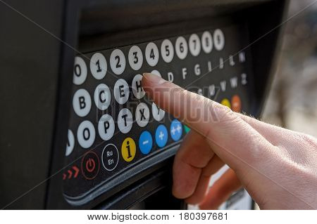 Close up of male hand pressing buttons on parking meter with colorful buttons in the street