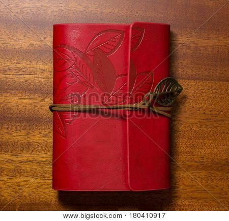 Red notebook with tape on a wooden table