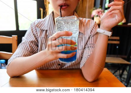 Young Woman Drinking Glass Of Splash Blue Lemon Juice Soda On The Wood Table, Suumer And Fresh Conce