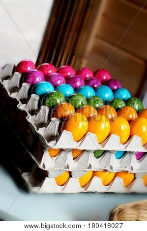 Stacked molded pulp egg carton with colorful bright rainbow painted easter eggs. Selected focus.