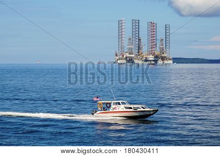 Labuan,Malaysia-Mac 25,2017:A speed boat moving with the view of of the lay up drilling jackup rigs in Labuan waters in the Brunei Bay area at Labuan island,Malaysia on 25th March 2017.