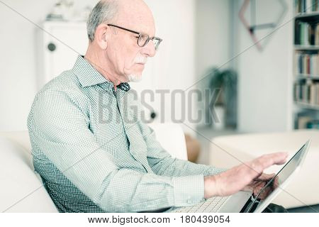 Senior Man Working With Laptop On Couch At Home.