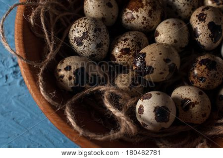 Quail Eggs In Wooden Bowl Isolated On Blue Background Close Up
