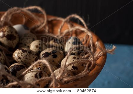 Quail Eggs In Wooden Bowl Isolated On Blue Background Close Up