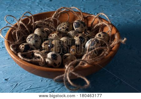 Quail Eggs In Wooden Bowl Isolated On Blue Background Close Up