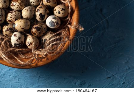 Quail Eggs In Wooden Bowl Isolated On Blue Background Close Up