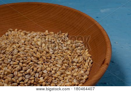 Wooden Bowl With Pearl Barley Isolated On Blue Background. Close-up.