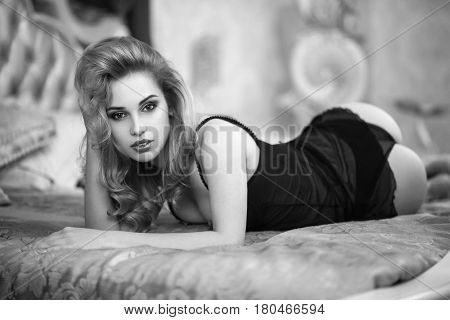 Beautiful model with perfect body lying on her bed in black lace lingerie. Shooting in a hotel room. Very sexy and sensual woman.