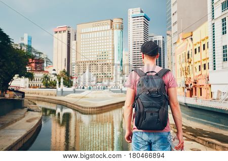 Young tourist watching on modern city with high-rise and old traditional buildings and Masjid Jamek Mosque in Kuala Lumpur