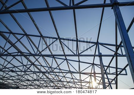 Galvanized steel roof truss construction frames with setting sun in the background