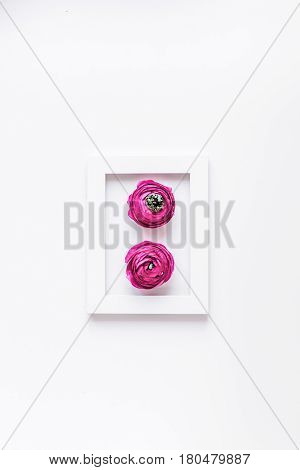Modern spring design with bright pink flowers in frame on white desk background top view moke up