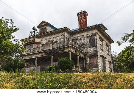 Large old house on a gloomy day in Astoria WA. The house is constructed of wood with a brick chimney.